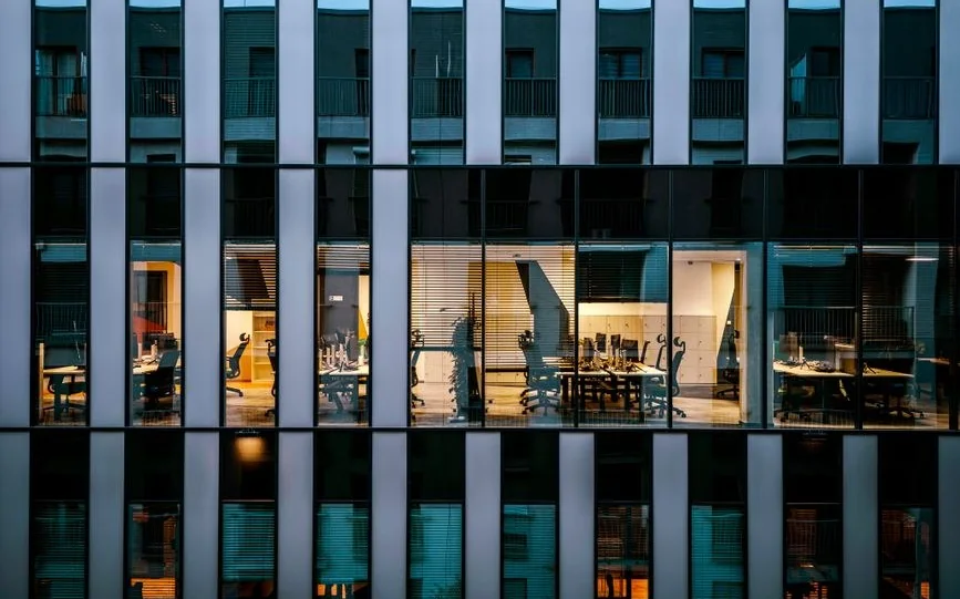 Alacakaranlıkta tek bir katı aydınlatılmış modern ofis binası cephesi