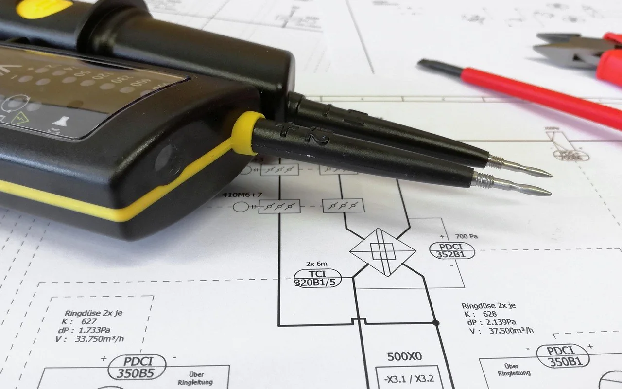 Elektrik projesi çizimi üzerine bırakılmış multimetre ve probları