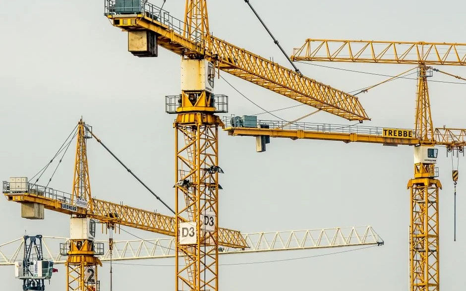 Açık gökyüzüne karşı yan yana yükselen kule vincler