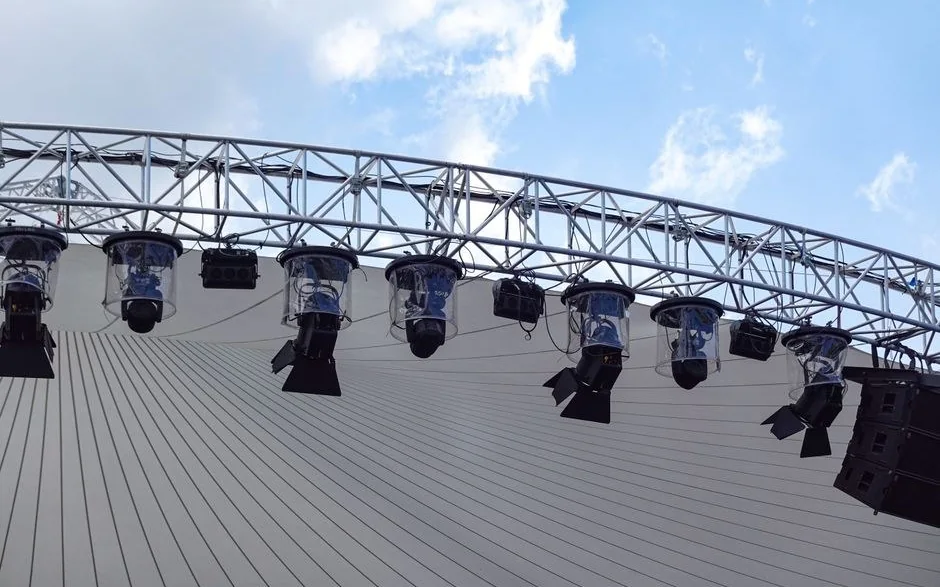 Gökyüzüne karşı duran sahne truss sistemi ve üzerine asılı robot ışıklar