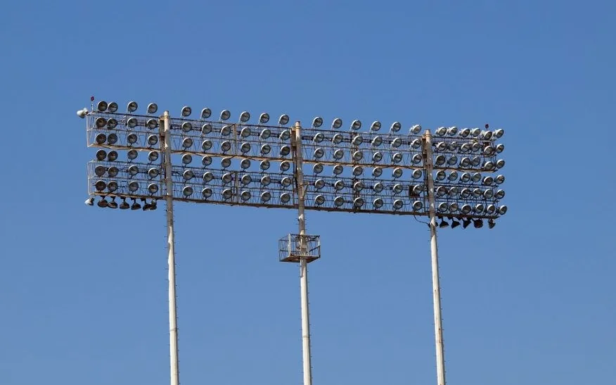 Mavi gökyüzüne karşı yan yana duran uç stadyum projektör direği
